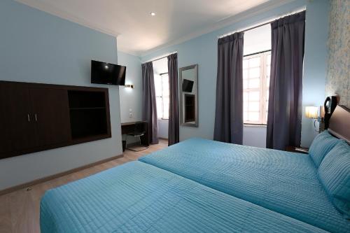 a bedroom with a blue bed and a flat screen tv at Pensao Praca Da Figueira in Lisbon