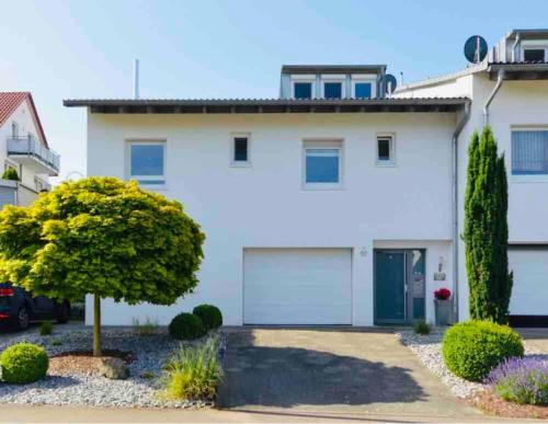 a white house with a garage and a tree at Modernes Apartment mit Küche, Parkplatz, WLAN - Nähe Schwäbisch Gmünd in Waldstetten