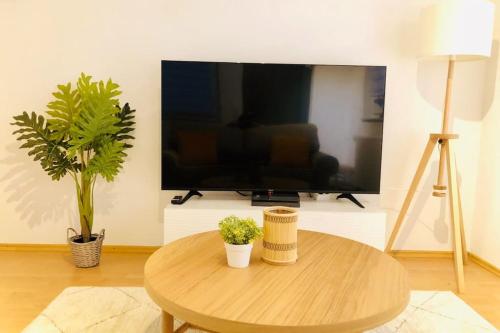 a living room with a table and a flat screen tv at Modernes Apartment in Waldstetten in Waldstetten