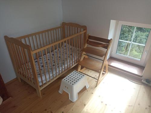 a crib and a chair in a room with a window at Chalupa v Českém lese in Bělá nad Radbuzou