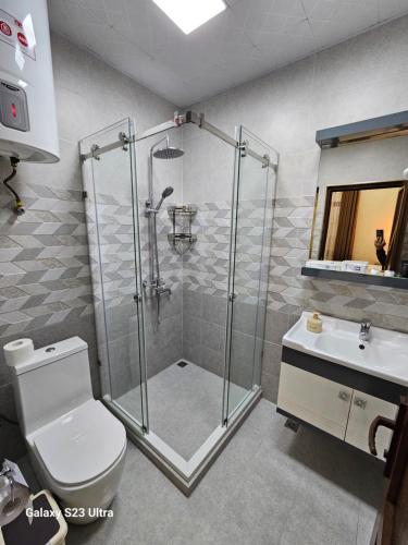 a bathroom with a shower and a toilet and a sink at Hotel Sharq in Dushanbe