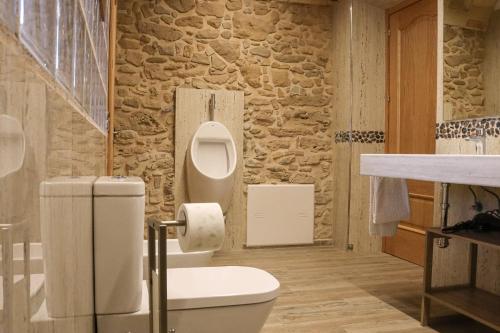 een badkamer met een toilet en een stenen muur bij Mas Manosa in Vilademuls