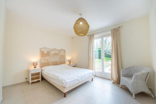 a bedroom with a bed and a chair and a window at Villa le Roi Soleil in Saint-Tropez