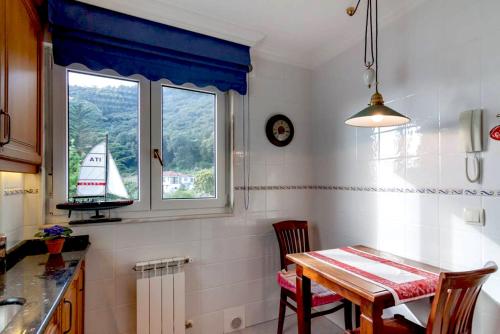 una cocina con mesa y un velero en una ventana en Duplex Playa Berria, en Piedrahita