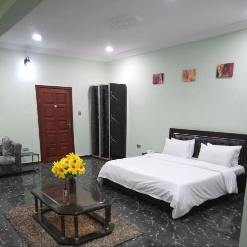 Un dormitorio con una cama grande y una mesa con flores en Teny Homes, en Calabar