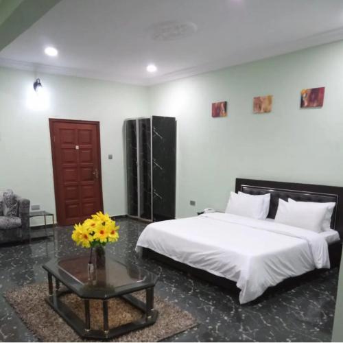 a bedroom with a large bed and a table with flowers at Teny Homes in Calabar