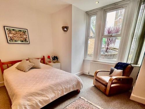 a bedroom with a bed and a chair and a window at Highbury boho apartment in London