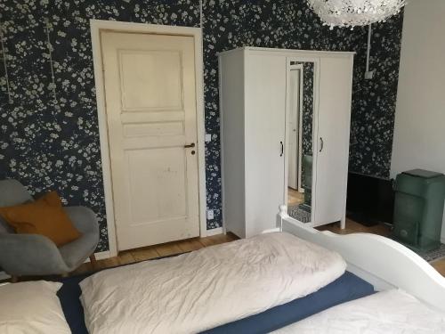 ein Schlafzimmer mit einem Bett, einem Stuhl und einer Tür in der Unterkunft Sinnerskog - Urlaub im alten Bahnhof in Högsby