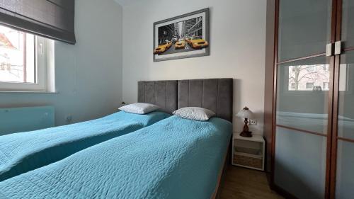 2 camas individuales en un dormitorio con sábanas azules en Apartament przy Parku Centralnym, en Gdynia