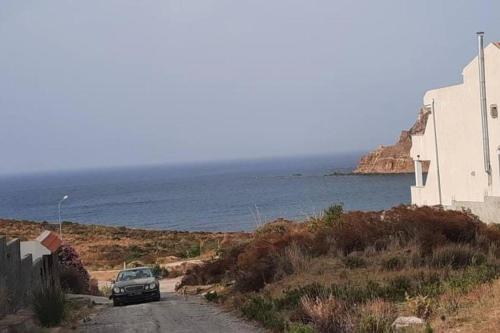 un coche aparcado en un camino de tierra junto al océano en Villa Vue sur Mer, en Tabarka