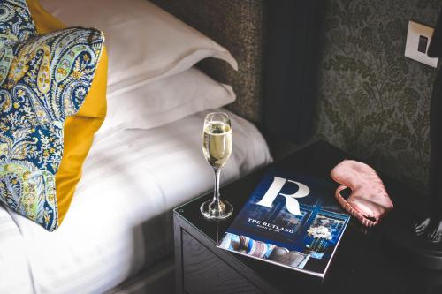 ein Glas Wein und ein Buch auf einem Tisch neben einem Bett in der Unterkunft The Rutland Hotel & Apartments in Edinburgh