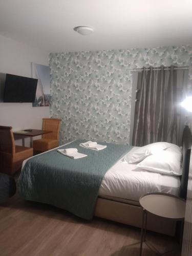 a bedroom with a bed and a table and chairs at Hotel La Voilerie Cancale bord de mer in Cancale