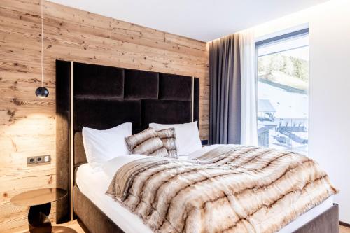 a bedroom with a large bed with a wooden wall at Hollywood Dream Penthouse with private Sauna close Ischgl in Kappl