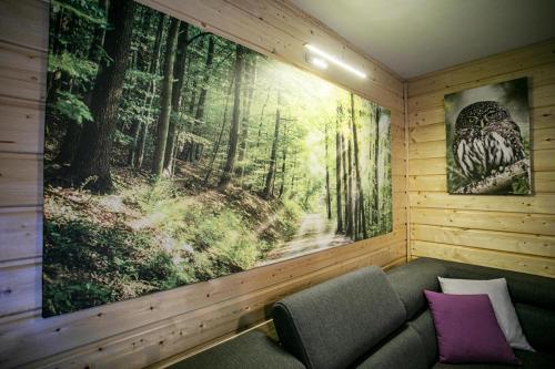 a room with a large painting of a forest at Domek całoroczny SÓWKA na Kaszubach z banią i sauną na wyłączność, wspólny basen i bilard z domkiem Jeleniówka - Ostrowite Leśna Dolina in Sulęczyno