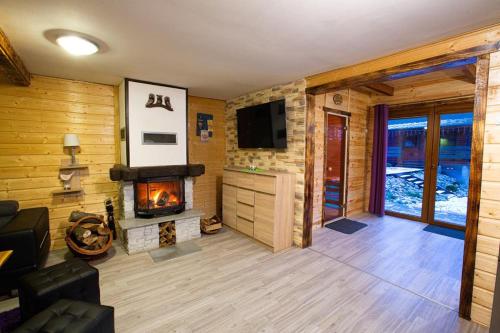 a living room with a fireplace and a television at Domek całoroczny SÓWKA na Kaszubach z banią i sauną na wyłączność, wspólny basen i bilard z domkiem Jeleniówka - Ostrowite Leśna Dolina in Sulęczyno