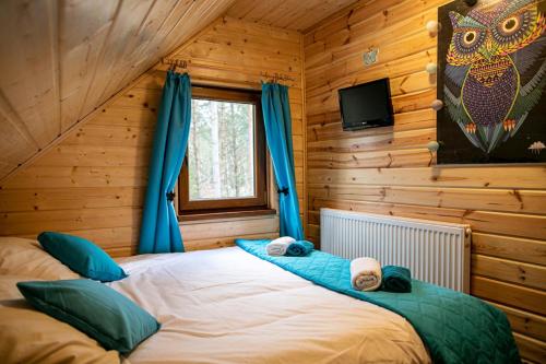 a bedroom with a large bed with blue curtains at Domek całoroczny SÓWKA na Kaszubach z banią i sauną na wyłączność, wspólny basen i bilard z domkiem Jeleniówka - Ostrowite Leśna Dolina in Sulęczyno