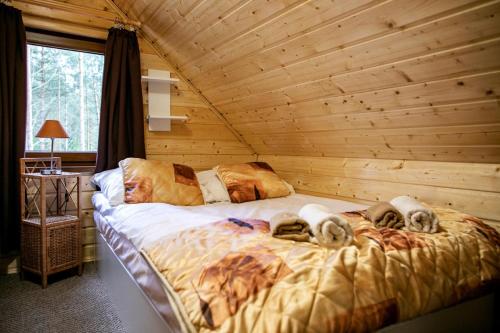 a bedroom with a bed in a log cabin at Domek całoroczny SÓWKA na Kaszubach z banią i sauną na wyłączność, wspólny basen i bilard z domkiem Jeleniówka - Ostrowite Leśna Dolina in Sulęczyno