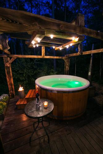 a jacuzzi tub on a deck with a table at Domek całoroczny SÓWKA na Kaszubach z banią i sauną na wyłączność, wspólny basen i bilard z domkiem Jeleniówka - Ostrowite Leśna Dolina in Sulęczyno
