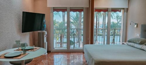 Schlafzimmer mit einem Bett, einem Tisch und einem TV in der Unterkunft Alicantissima Marina & Beach in Alicante