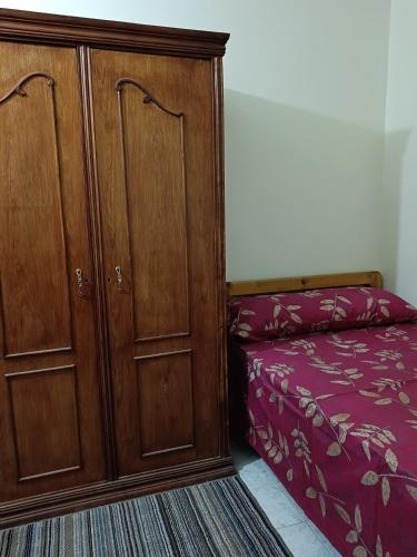 a bedroom with a bed and a wooden cabinet at النخلة 8 in Mansoura
