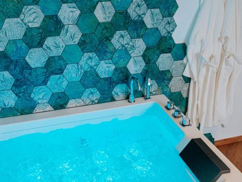 baño con piscina y pared de azulejos en L'Oasis Tropicale, en Roppenheim