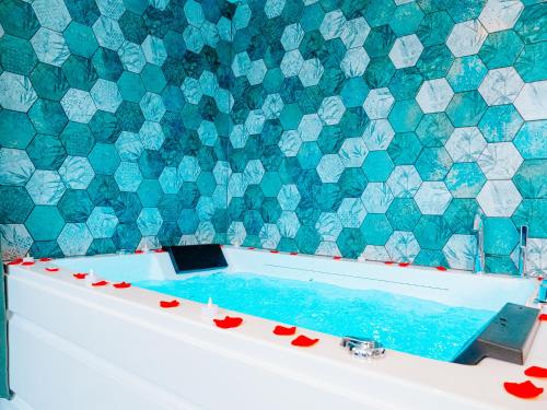 bañera con pared de azulejos azules y blancos en L'Oasis Tropicale, en Roppenheim