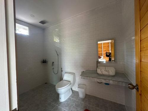 La salle de bains blanche est pourvue de toilettes et d'une fenêtre. dans l'établissement Koh Yao Beach Front, à Ko Yao Yai