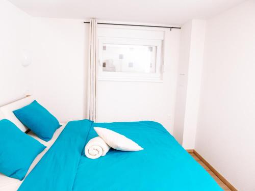 a blue bed in a white room with a window at La Suite Cosy in Roppenheim