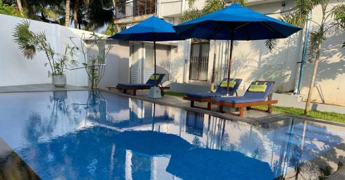 una piscina con due ombrelloni blu e due sedie di Ranil Villa a Galle