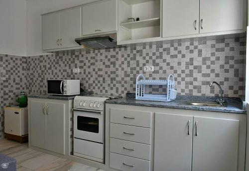 uma cozinha com armários brancos, um lavatório e um micro-ondas em TARRAFAL SN TOUR em Tarrafal