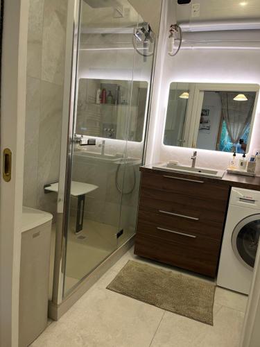 a bathroom with a shower and a sink and a washing machine at Luxueux appartement 4 personnes - Parking gratuit - 20 min de Paris in Asnières-sur-Seine