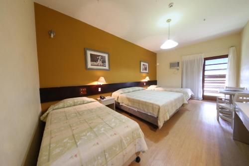 een hotelkamer met 2 bedden, een tafel en een bureau bij Hotel Península in Avaré