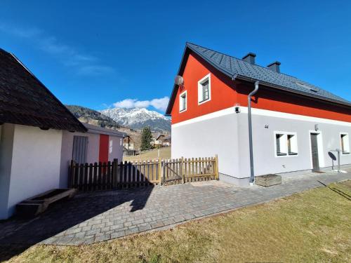 a red and white house with mountains in the background at Schlömmerhaus in Michaelerberg