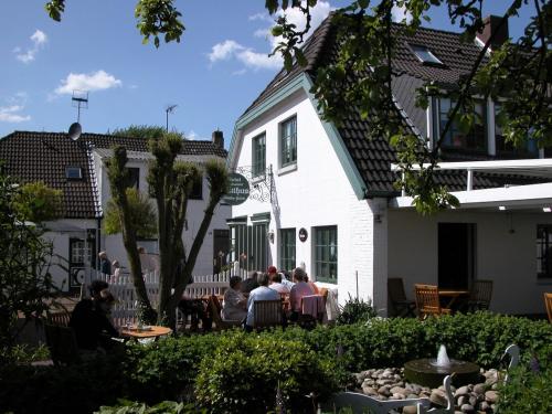 un grupo de personas sentadas fuera de una casa blanca en Hotel Witthus GmbH & CoKG, en Greetsiel
