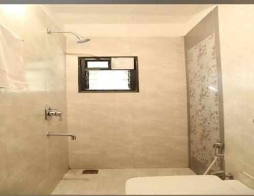 a bathroom with a shower with a toilet and a window at Hotel Ocsa Inn in Nagpur