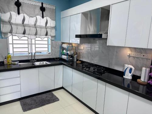 Pokok Sena的住宿－Homestay Sejahtera，厨房配有白色橱柜和黑色台面