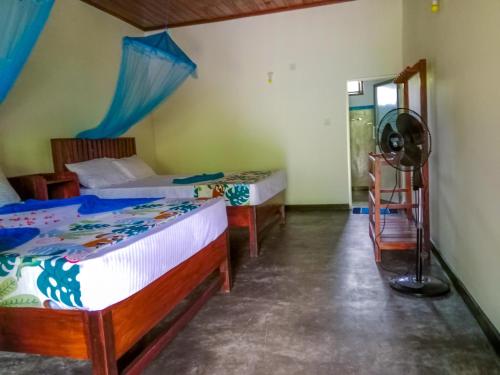 a bedroom with two beds and a fan at Pride Rock Villa & Tree House in Sigiriya