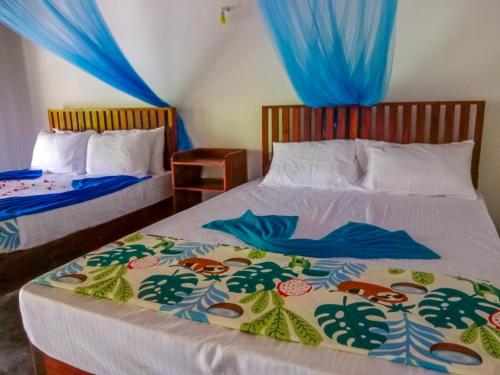 two beds in a bedroom with blue drapes at Pride Rock Villa & Tree House in Sigiriya