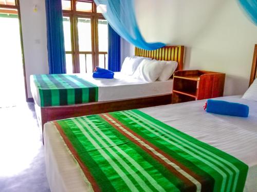 a bedroom with two beds with blue curtains and a window at Pride Rock Villa & Tree House in Sigiriya