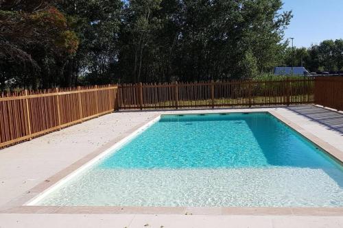 une piscine avec une clôture en bois et de l'eau bleue dans l'établissement SUPERBE VILLA NEUVE, 5MN A PIEDS DES PLAGES A VIAS, à Vias