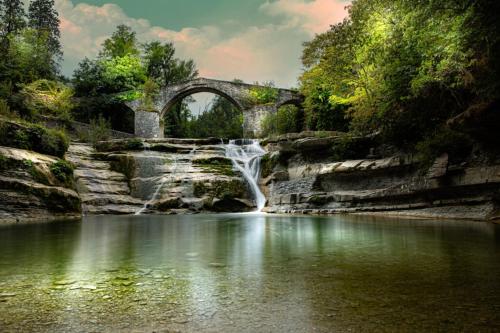una cascata in un fiume con ponte di I Due Cervi a Portico di Romagna