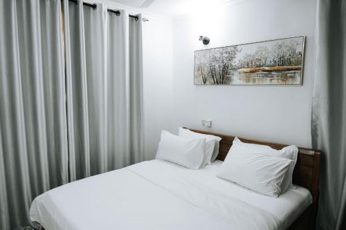 una camera da letto con letto, lenzuola e cuscini bianchi di Cozy 2 bedroom with Gym a Dar es Salaam