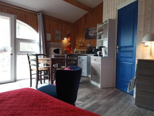 eine Küche mit einer blauen Tür und einem Tisch mit Stühlen in der Unterkunft Espace Nature Studio indépendant proche du Parc des oiseaux in Sainte-Olive