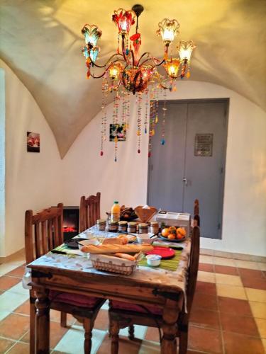 a table with food on it with a chandelier at Les chambres du roc St Jean in Gluiras