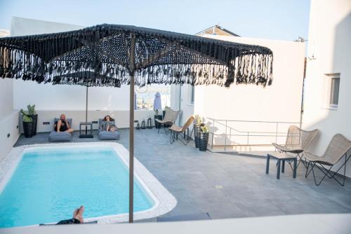 a pool with people sitting in chairs and an umbrella at Aidani Luxurious Rooms in Vóthon
