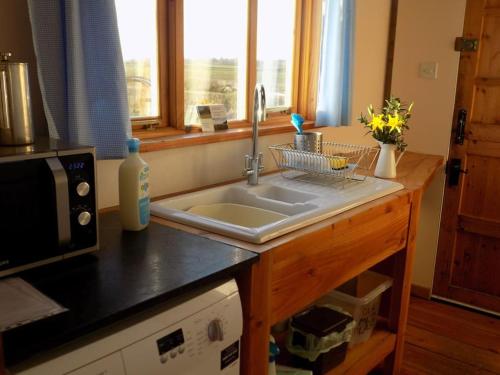 a kitchen counter with a sink and a window at Log Cabin at The Old Summer Dairy Glastonbury in Somerton
