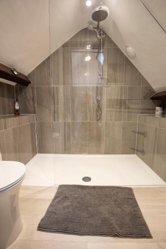 a bathroom with a shower with a toilet and a rug at Central Stow on the Wold in Stow on the Wold