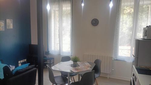 a dining room with a table and chairs and windows at F1 duplex Bleuet Rénové in Lamalou-les-Bains