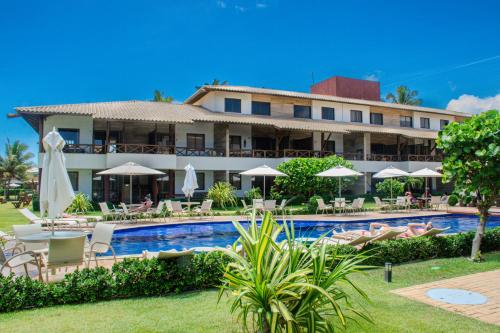 a resort with a pool and chairs and umbrellas at Itacimirim Apartments Boulevard e Ondas in Itacimirim