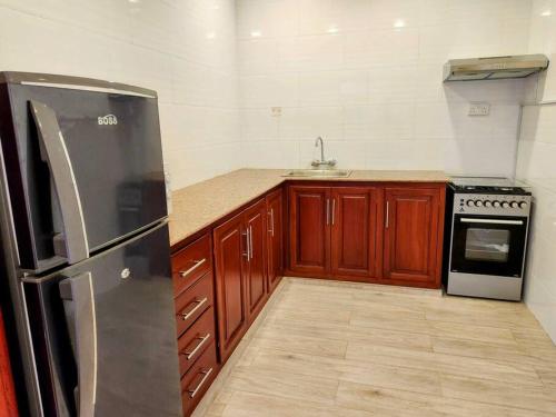 La cuisine est équipée d'armoires en bois et d'un réfrigérateur en acier inoxydable. dans l'établissement Cozy 2 bedroom in Moshi Town, à Moshi